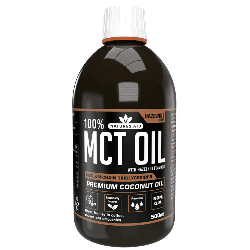 Natures Aid 100% MCT Oil with Hazelnut Flavor in a 500ml bottle, with the oil poured into a clear glass and hazelnuts nearby.