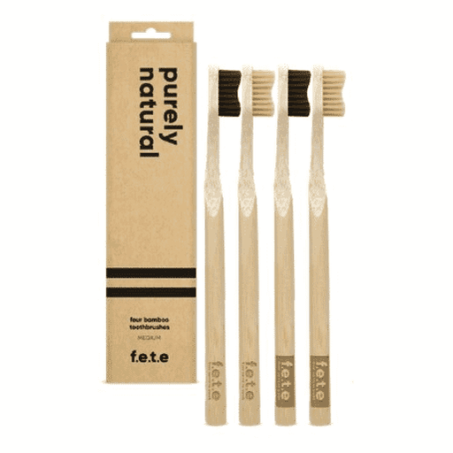 Set of four F.E.T.E bamboo toothbrushes with medium bristles, showcasing eco-friendly design and natural bamboo handles.