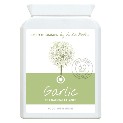 Fresh garlic cloves in a Just For Tummies Garlic supplement bottle, 60 capsules, with garlic bulbs in the background.